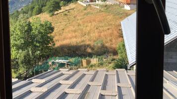 Une vue sur un paysage montagneux avec une cabane en bois et un bâtiment doté d’un toit en pente.