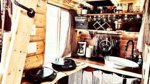 A compact kitchen with wooden cabinets, a coffee machine, and a record player.