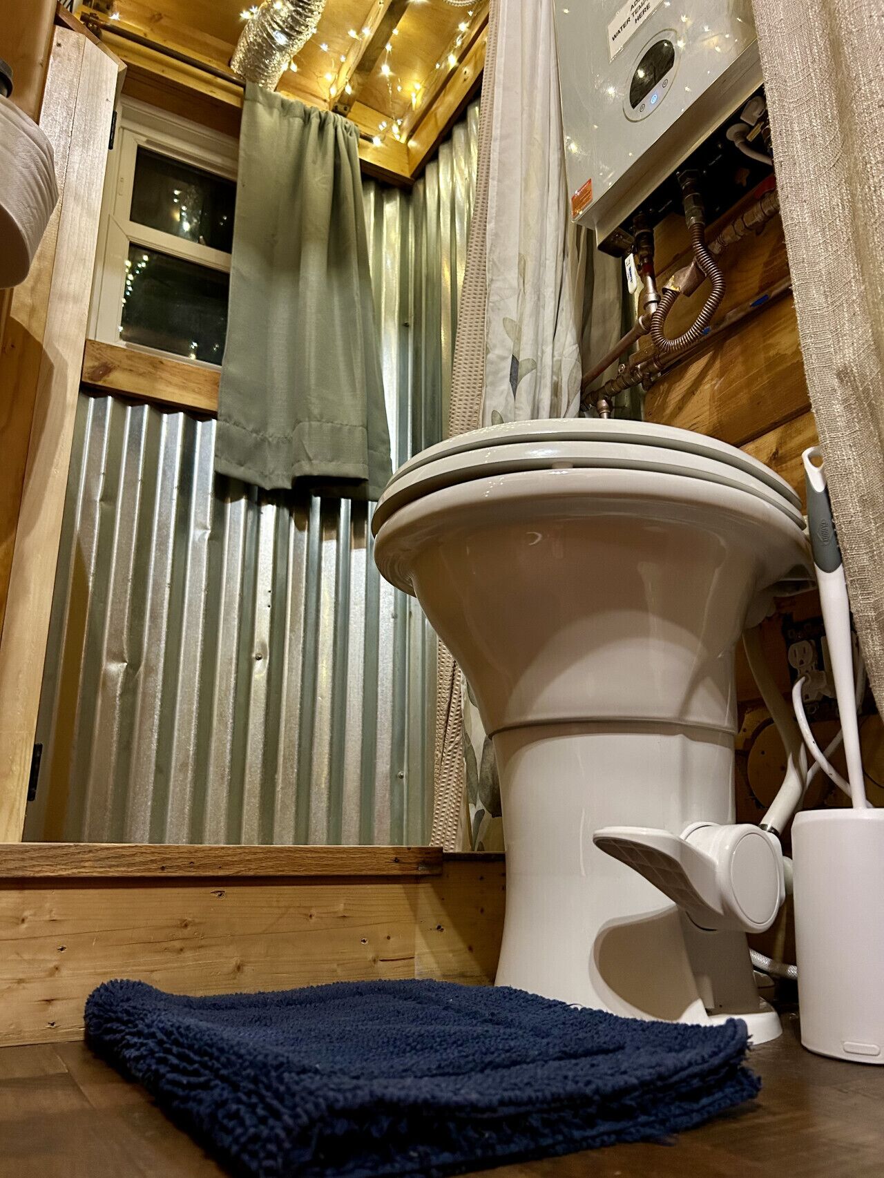 Een badkamer met toilet, douche en een raam met gordijnen.