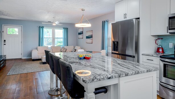 Una cocina moderna con gabinetes blancos, electrodomésticos de acero inoxidable y una isla de mármol.