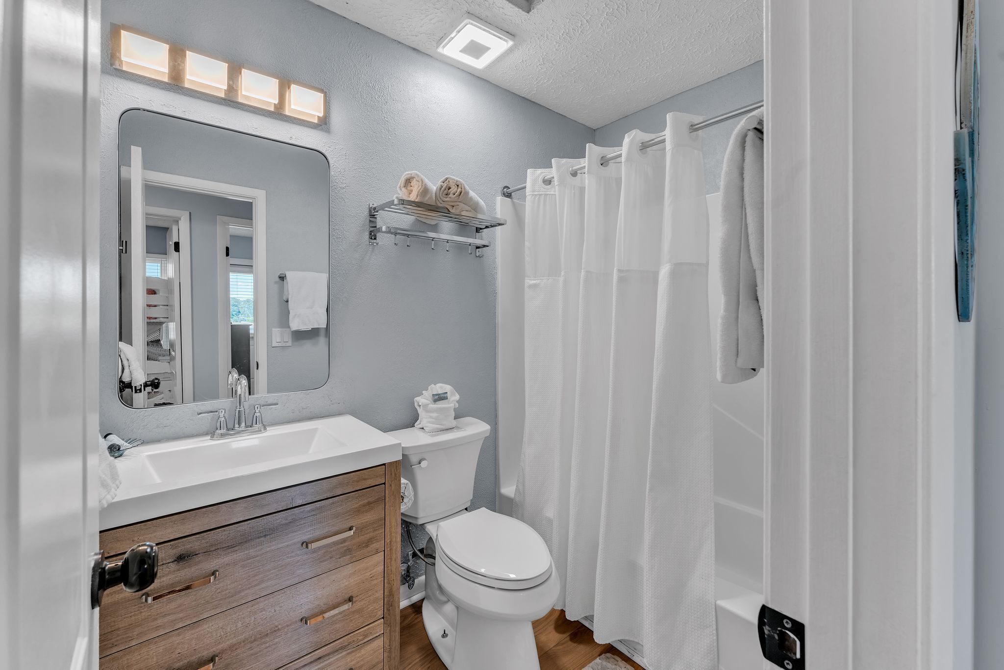 A modern bathroom with a white sink, wooden vanity, and a toilet.