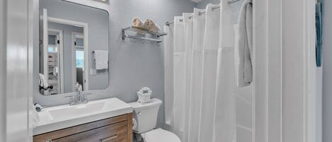 A modern bathroom with a white sink, wooden vanity, and a toilet.