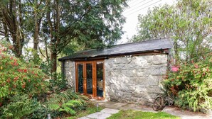 A stone building with a glass door and a small porch. - Carminow Barn (Bodmin)