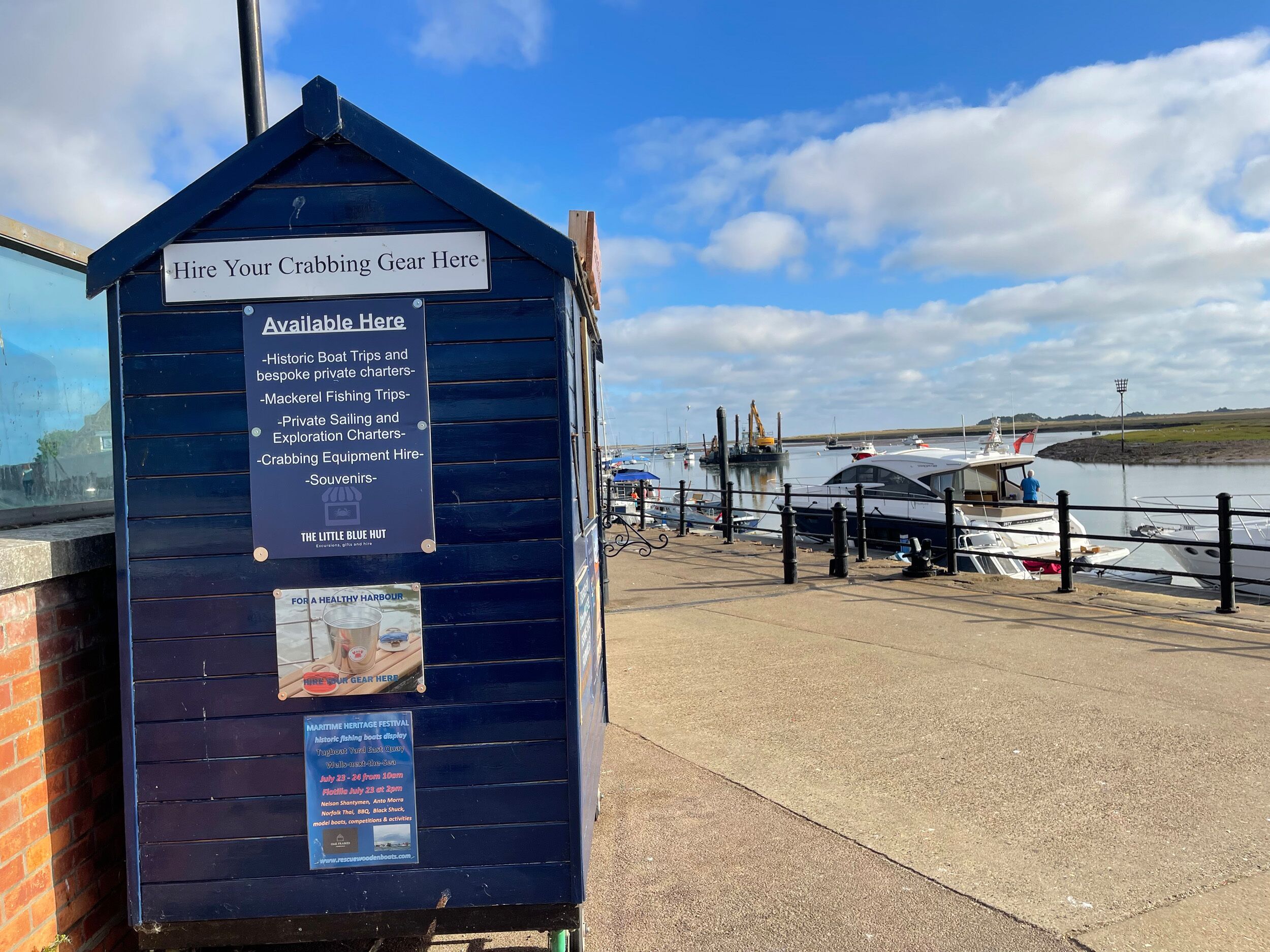 A wooden information board with text about hiring crabbing gear and available services.