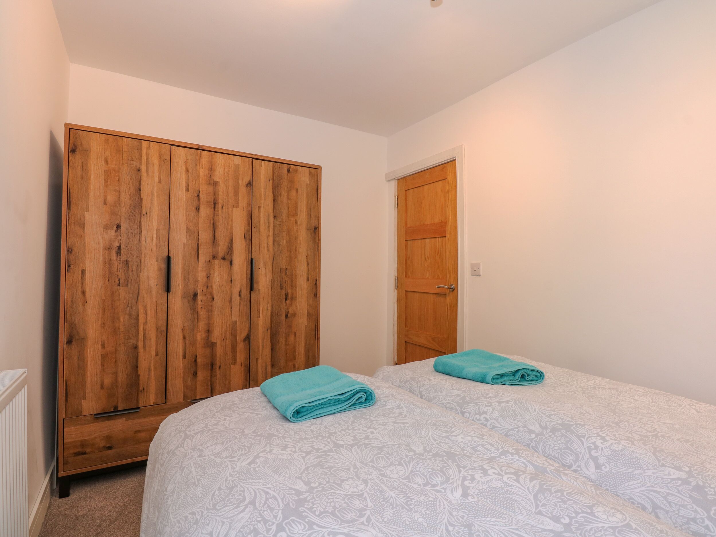 Una camera da letto con due letti, un armadio in legno e una porta.