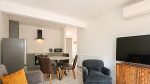 Ein modernes Wohnzimmer mit grauem Sofa, blauem Sessel und einer Holzkassette mit Flachbildfernseher.