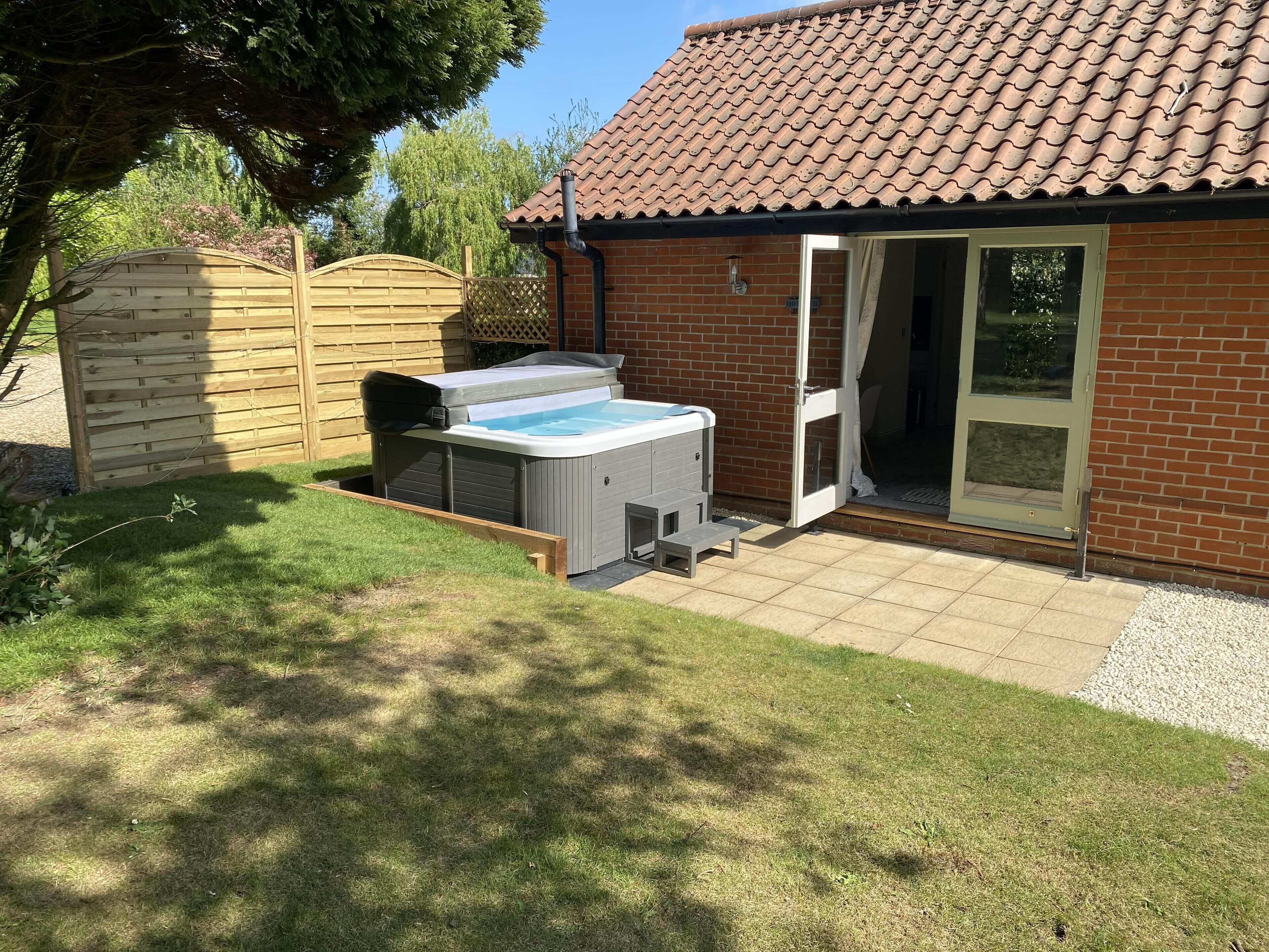 Ein Garten mit Whirlpool, Holzzaun und Ziegelhaus.