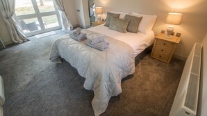 Une chambre d’hôtel avec un grand lit, une table de chevet, une lampe et une vue sur l’extérieur grâce à une porte coulissante.