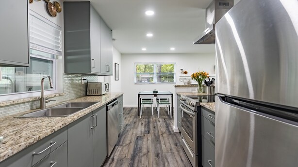 Una cocina moderna con encimeras de granito, electrodomésticos de acero inoxidable y un comedor con mesa y sillas.