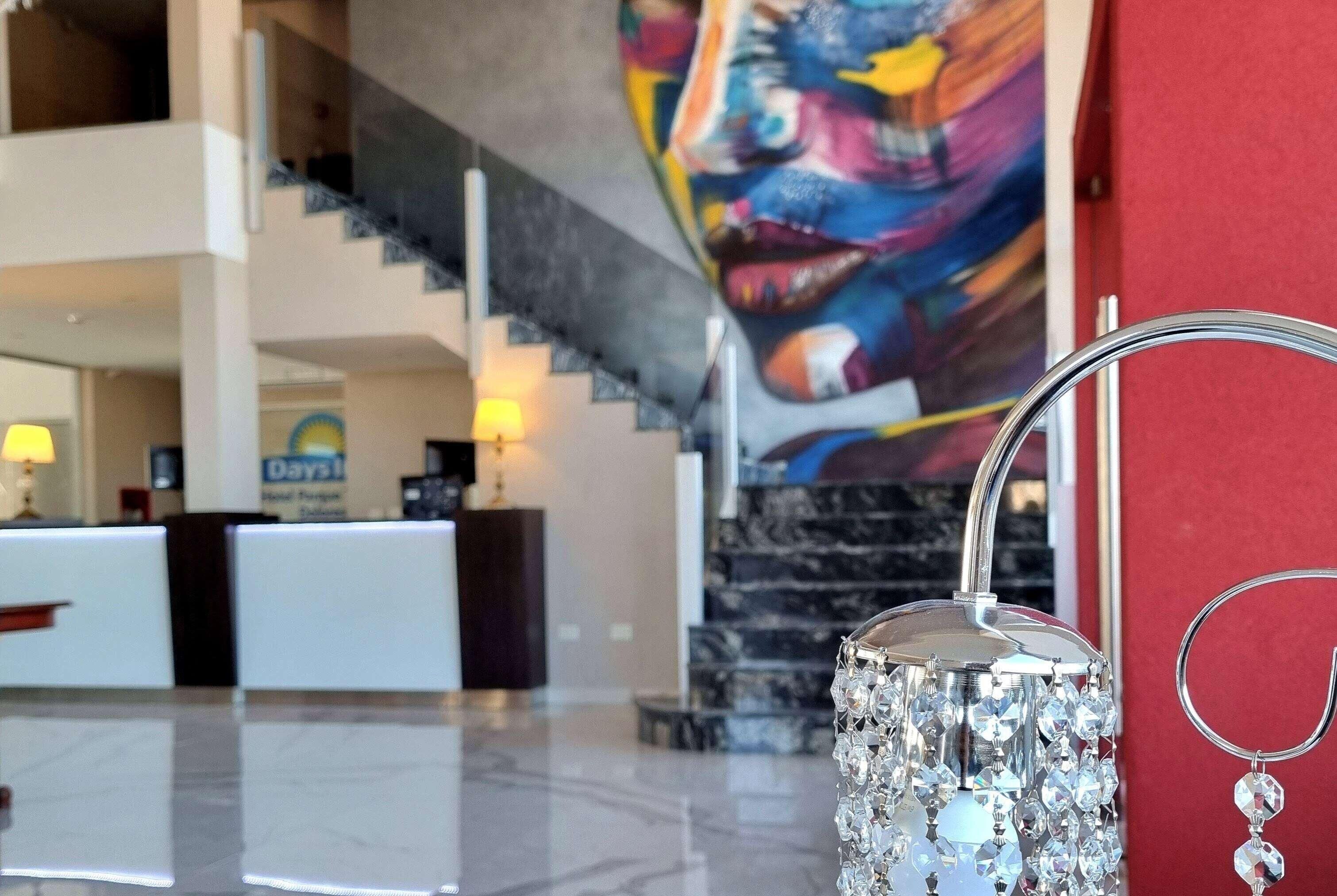 A lobby with a reception desk, a staircase, and a wall with a colorful abstract painting.
