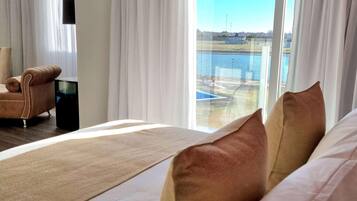 Habitación de hotel con cama, una silla, televisor y vista a un cuerpo de agua.