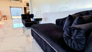 Un hall d’hôtel moderne avec un canapé noir, une petite table ronde et une grande fenêtre.