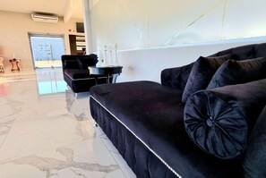 A modern hotel lobby with a black sofa, a small round table, and a large window. - Days Inn By Wyndham Dolores Hotel Termal (Dolores)