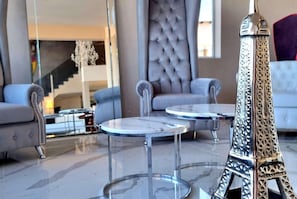 Een modern interieur met een glazen Eiffeltoren, twee ronde tafels en een gestoffeerde bank.