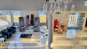 Un hall d’entrée spacieux, agrémenté d’un lustre, d’un coin salon et de grandes fenêtres.