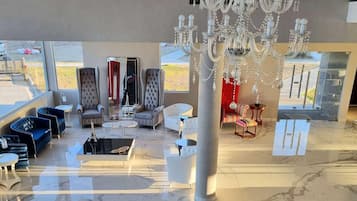 Un hall d’entrée spacieux, agrémenté d’un lustre, d’un coin salon et de grandes fenêtres.