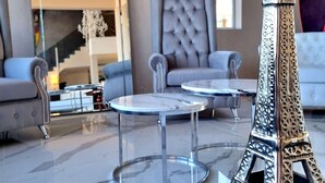 Un intérieur moderne avec une réplique de la tour Eiffel en verre, deux tables rondes et un canapé capitonné.
