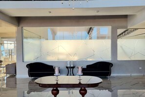 Een modern interieur met een glanzende marmeren vloer, een ronde tafel met twee vazen en twee zwarte banken.