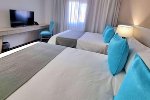 Une chambre d’hôtel avec deux lits, une télévision, un bureau et une chaise.