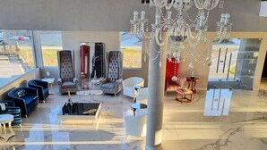 Un hall d’entrée spacieux, agrémenté d’un lustre, d’un coin salon et de grandes fenêtres.
