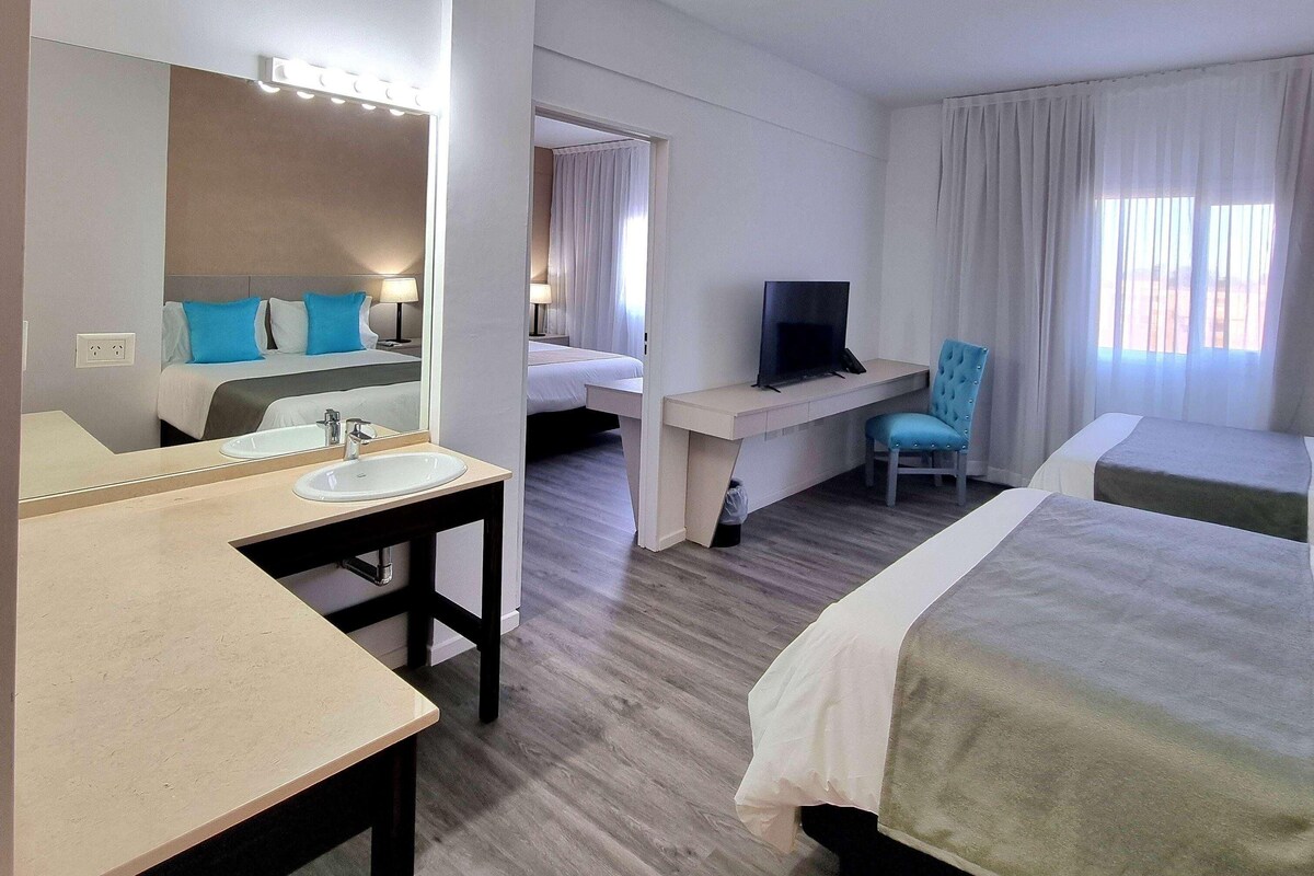 Habitació d'hotel amb llit, escriptori amb televisió, bany amb rentapous i mirall.