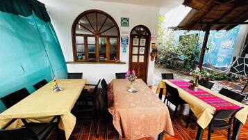Un espace repas avec des tables et des chaises, une fenêtre donnant sur un paysage agréable et une porte avec une pancarte.