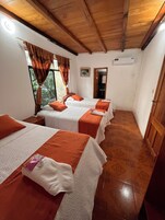 Una habitación con cuatro camas, cada una con un edredón blanco y naranja, y techo de madera.