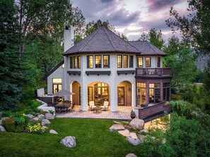 A two-story house with a large deck, a hot tub, and a well-maintained garden.