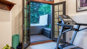 Une salle de sport à domicile équipée d’un tapis de course, de poids et d’un tapis de yoga.