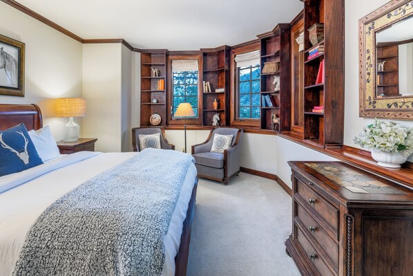 Un dormitorio con una cama grande, un escritorio, una silla, una estantería y un aparador.