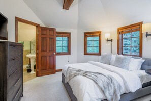 Un dormitorio con cama, cómoda y puerta que da a un baño.
