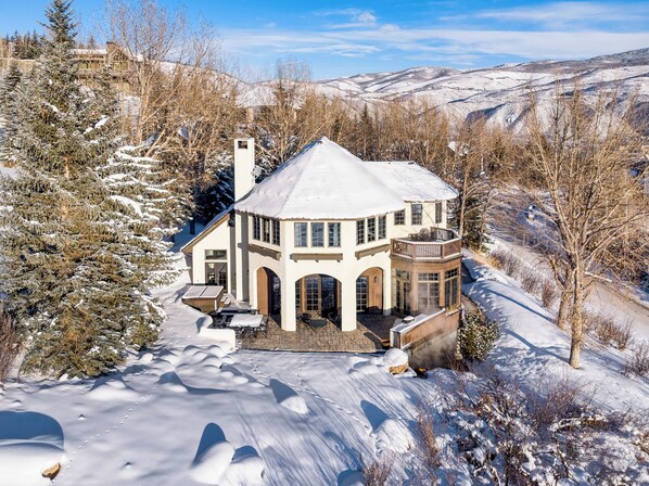 A snow-covered house with a large deck and multiple windows.