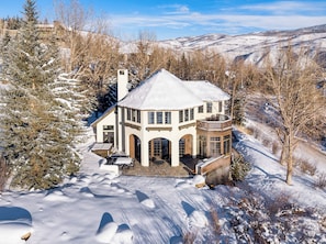 Una casa cubierta de nieve con un amplio balcón y numerosas ventanas.