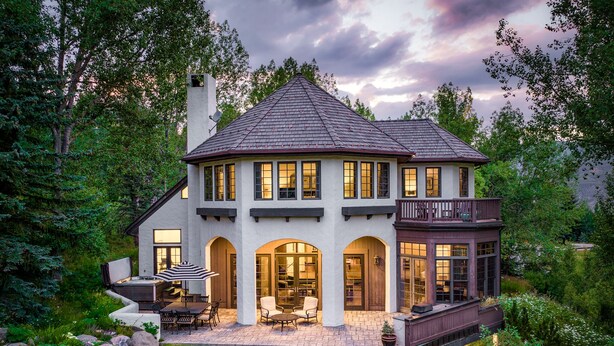 Une maison à deux étages avec une grande véranda à l’avant, de nombreuses fenêtres et un balcon.