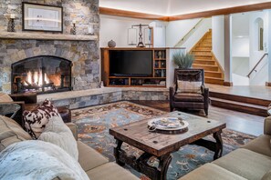 A cozy living room with a stone fireplace, a television, and comfortable seating.