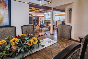 A dining area with a wooden table, wicker chairs, and a floral centerpiece.