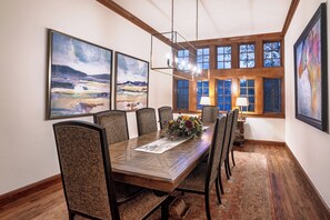 Ein Esszimmer mit einem Holztisch, gewobenen Stühlen und Bildern an den Wänden.