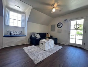 Relax in this spacious living room with a high ceiling, large window, and comfortable sofa.