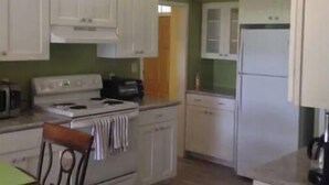 Una cocina con gabinetes blancos, estufa y refrigerador.