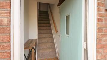 A staircase leading to a room with a wooden bench and a light blue door.