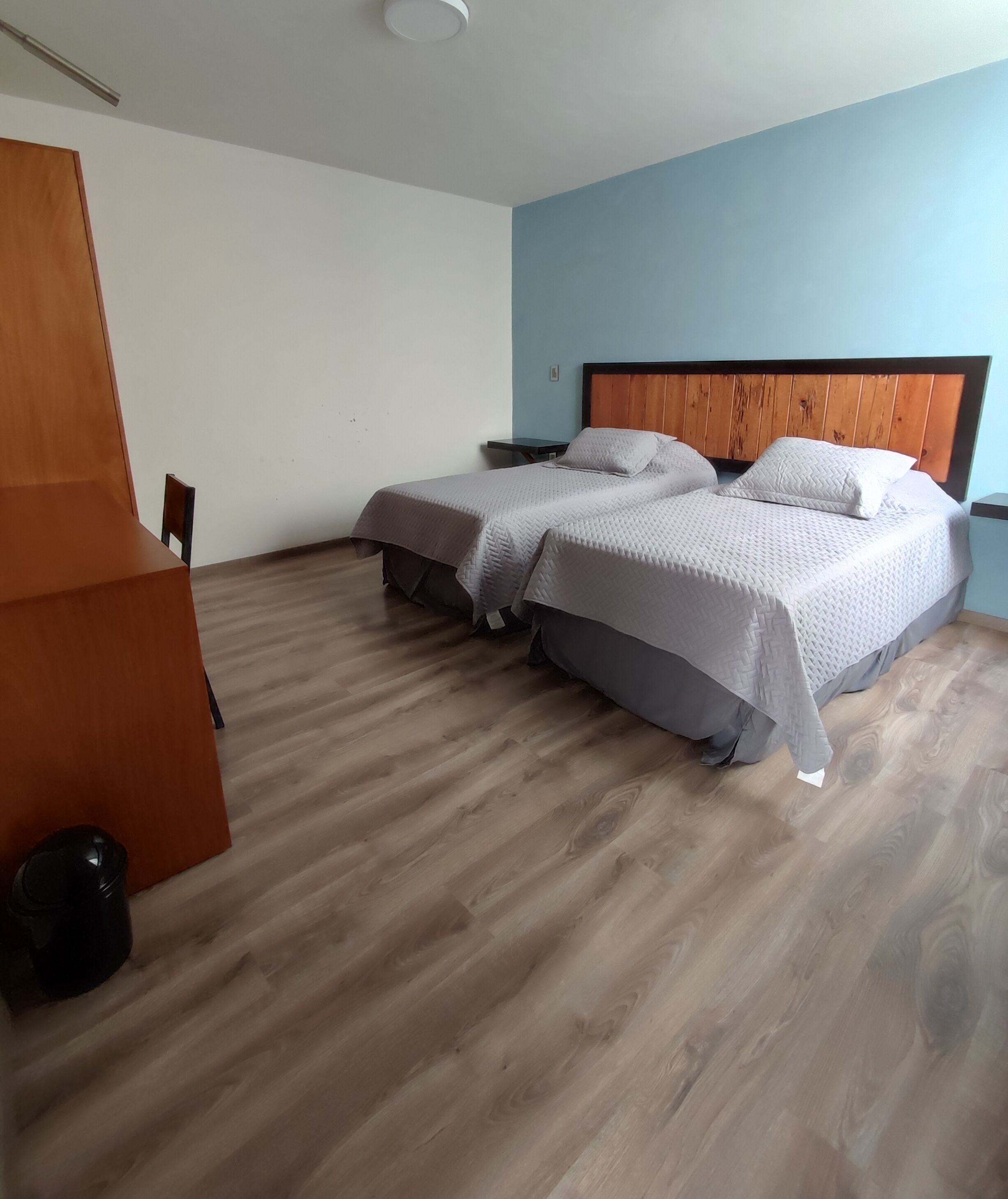 A bedroom with two beds, a wooden desk, and a chair.