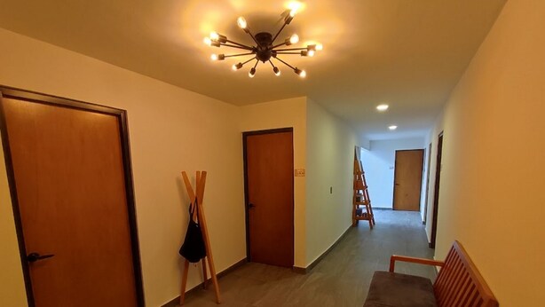 A hallway with wooden doors, a bench, and a ceiling light fixture. - El salto de Camela (Uruapan)