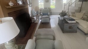 A spacious living room with a fireplace, a staircase, and a view of the outdoors. - Classic, on the water stunner! Owner occupied with full amenities! (Saint George)