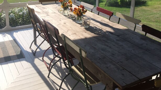 A covered outdoor dining area with a wooden table, chairs, and a vase of flowers. - Classic, on the water stunner! Owner occupied with full amenities! (Saint George)
