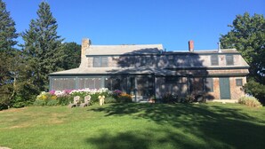 A two-story house with a large front porch, a covered entryway, and a well-maintained lawn. - Classic, on the water stunner! Owner occupied with full amenities! (Saint George)