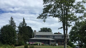 A house with a large front yard, a wooden deck, and a stone wall. - Classic, on the water stunner! Owner occupied with full amenities! (Saint George)
