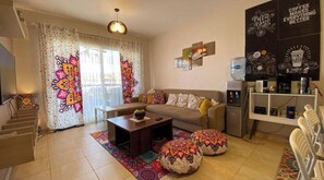 Relax in this inviting living space with a sofa, coffee machine, and water dispenser. Enjoy the convenience of a staircase leading to an upper level.