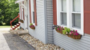 Une maison avec un porche, des volets rouges et des jardinières.