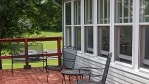 Une véranda avec une terrasse en bois, des chaises en métal et une table.
