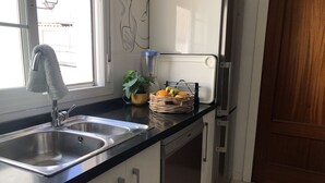 Eine Küche mit Spüle aus Edelstahl, einer Topfpflanze und einer Fruchtkorb auf der Arbeitsfläche.